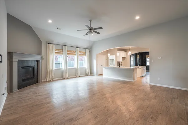 an empty room with wooden floor fireplace and windows