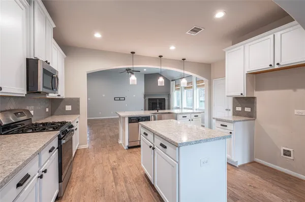 a large kitchen with stainless steel appliances lots of counter space and wooden floor