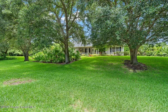a front view of a house with a garden and trees