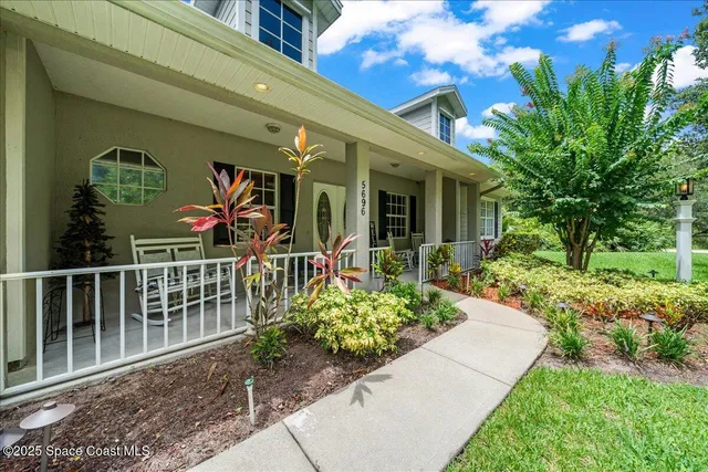a view of a house with potted plants and a bench