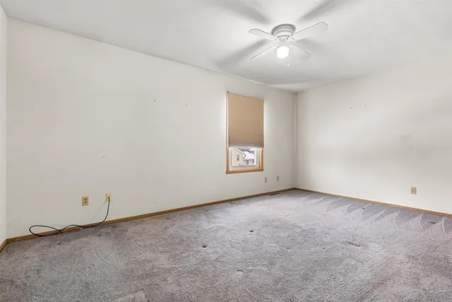 an empty room with a chandelier fan and windows