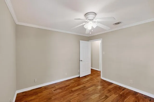 an empty room with wooden floor fan and windows