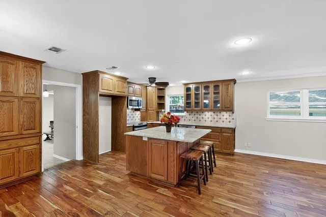 a kitchen with stainless steel appliances a dining table chairs refrigerator and sink