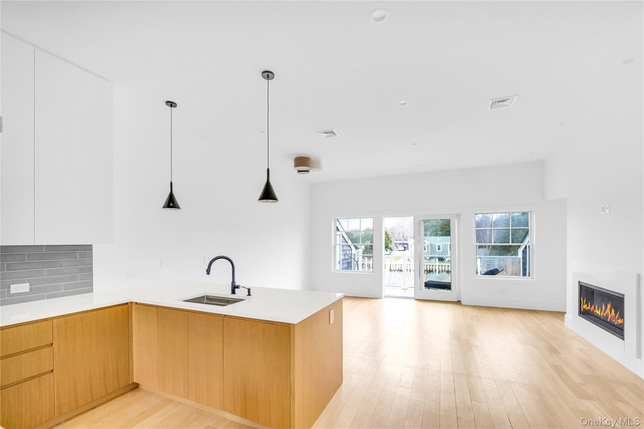 68 Foster Avenue, Unit 4 Hampton Bays, NY 11946 - Photo 4 of 17 a view of a kitchen with kitchen island a sink wooden floor and windows