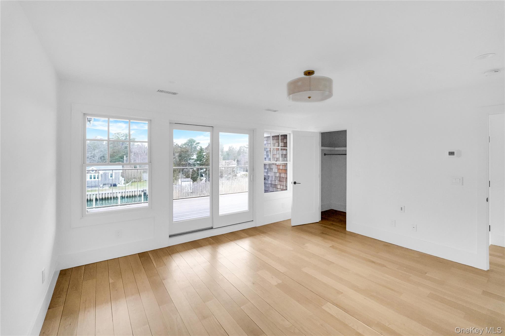 68 Foster Avenue, Unit 4 Hampton Bays, NY 11946 - Photo 10 of 17 an empty room with wooden floor and windows