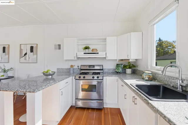 a kitchen with stainless steel appliances granite countertop a sink stove and white cabinets