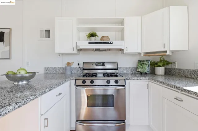 a kitchen with granite countertop white cabinets and stainless steel appliances