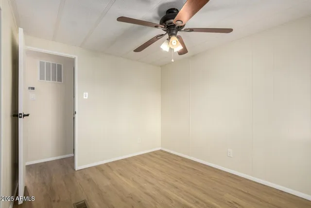an empty room with wooden floor fan and windows