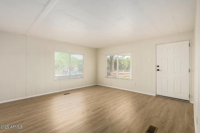 an empty room with wooden floor and windows