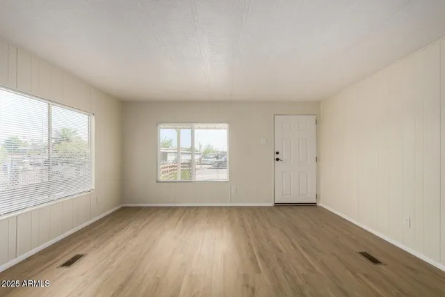 an empty room with wooden floor and windows