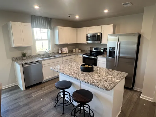 a kitchen with stainless steel appliances granite countertop a sink a stove a refrigerator cabinets and dining table