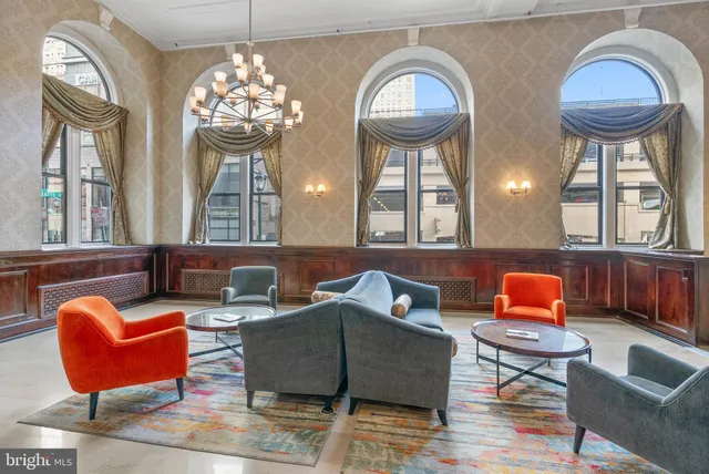 a living room with couches a fireplace and four mirrors