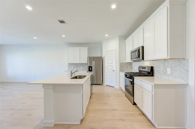 a kitchen with stainless steel appliances a sink stove top oven and white cabinets
