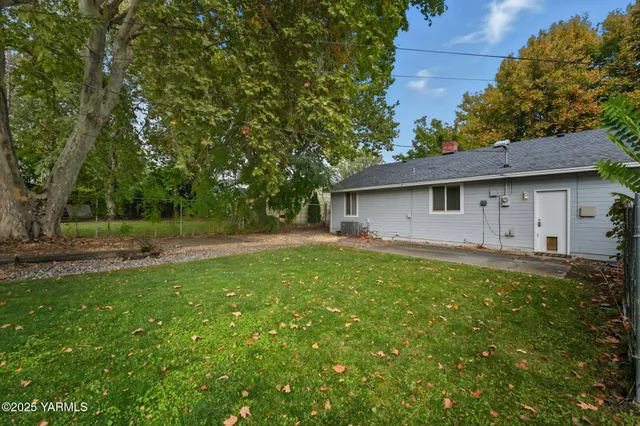 a backyard of a house with plants and large trees