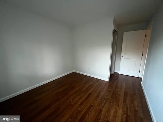 a view of an empty room with wooden floor and closet