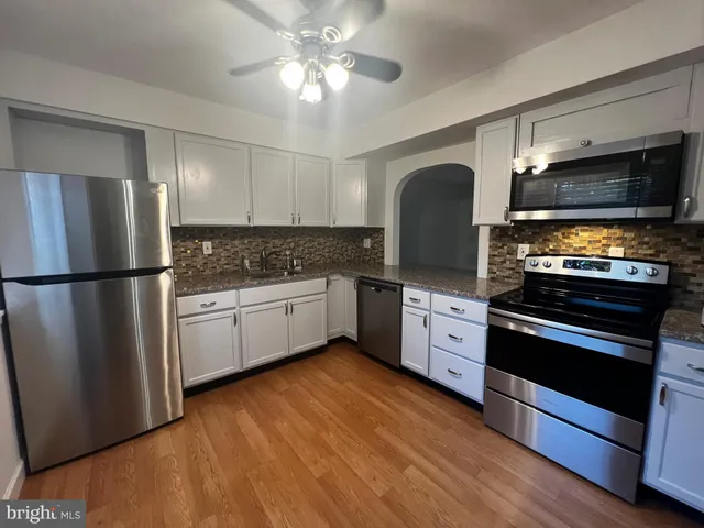 a kitchen with stainless steel appliances white cabinets and a refrigerator