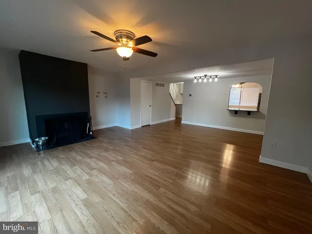 a view of an empty room with wooden floor and a chandelier fan