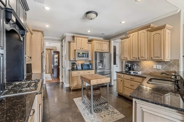 a kitchen with stainless steel appliances granite countertop sink stove refrigerator and cabinets