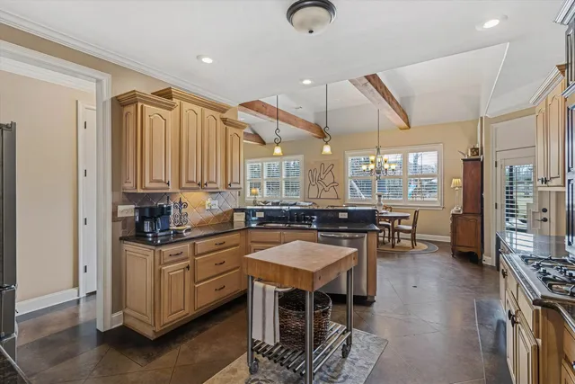 a kitchen with stainless steel appliances kitchen island granite countertop a table chairs in it and wooden floors