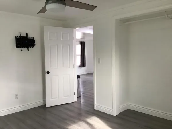 an empty room with wooden floor and a ceiling fan