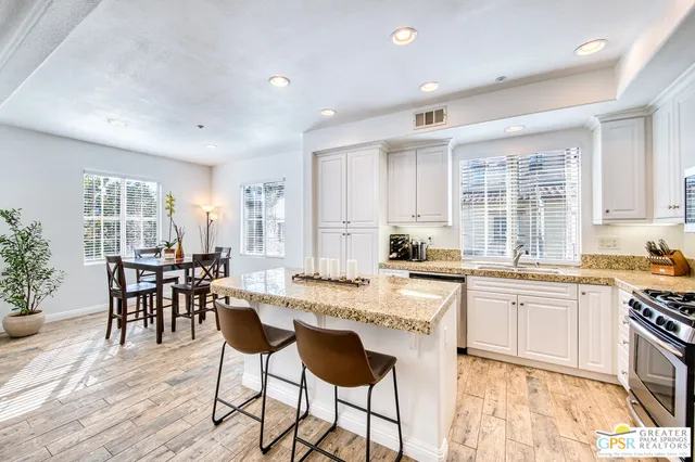 a large kitchen with kitchen island granite countertop a dining table chairs and white cabinets