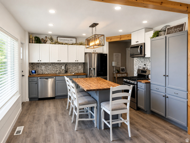 303 North Main Street Grace, ID 83241 - Photo 9 of 22 Kitchen featuring a central island with wood-finish countertop, stainless steel appliances, two-tone cabinetry, mosaic tile backsplash, and wood-finish flooring