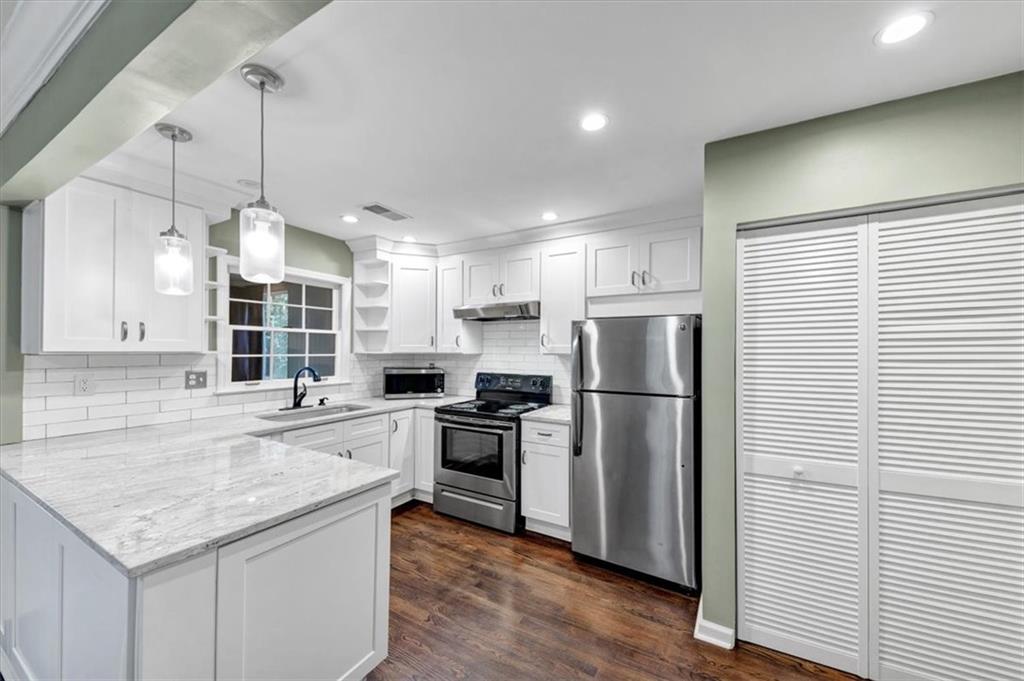 a kitchen with refrigerator a stove and wooden floor