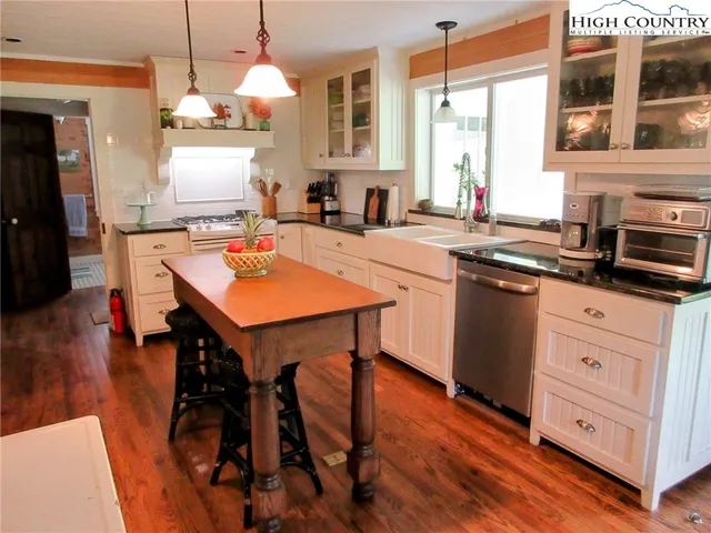 a kitchen with stainless steel appliances granite countertop a stove a sink dishwasher a stove a dining table and chairs with wooden floor