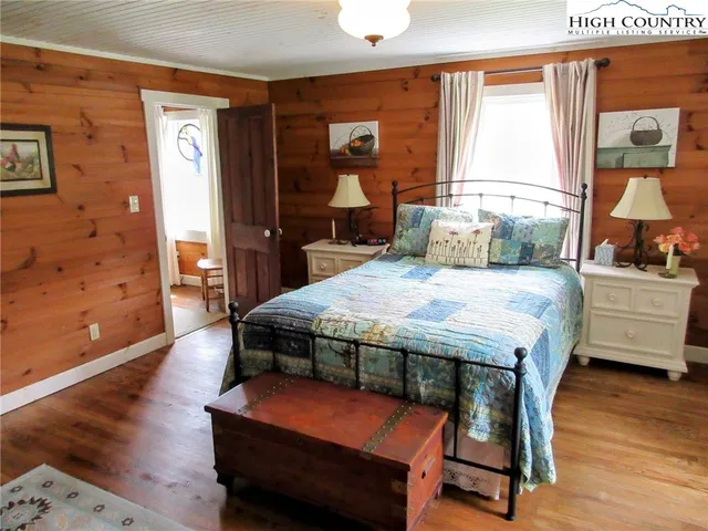 a bedroom with a bed a dresser and next to a window