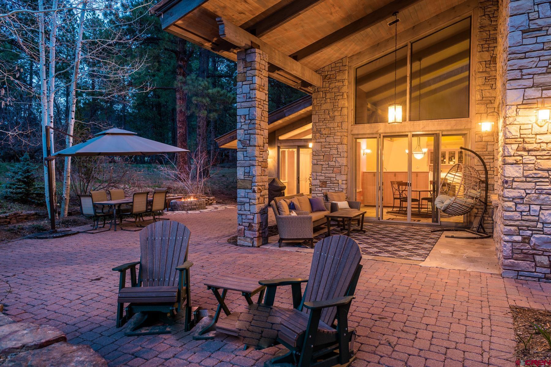 47 Mason Cabin Road Durango, CO 81301 - Photo 10 of 35 a view of a patio with a dining table and chairs under an umbrella with a barbeque