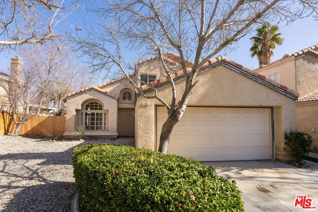 a view of a white house with a yard and large tree