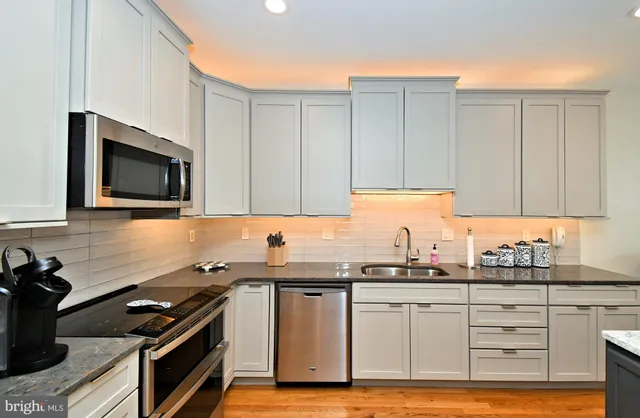 a kitchen with granite countertop a sink a stove and cabinets