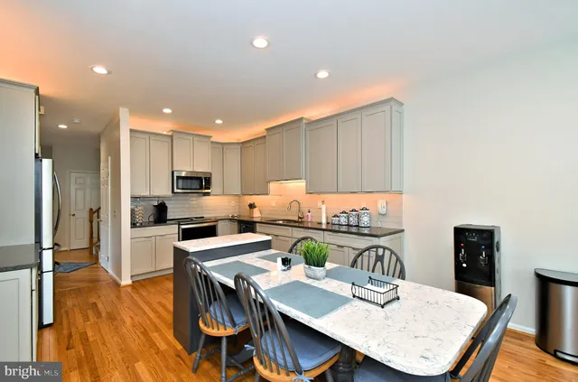 a open dining room with stainless steel appliances wooden floor dining table and chairs