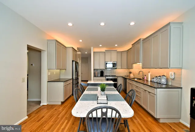 a kitchen with stainless steel appliances granite countertop a kitchen island hardwood floor sink and stove
