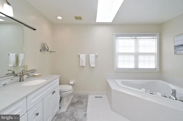 a bathroom with a tub a sink and a large mirror