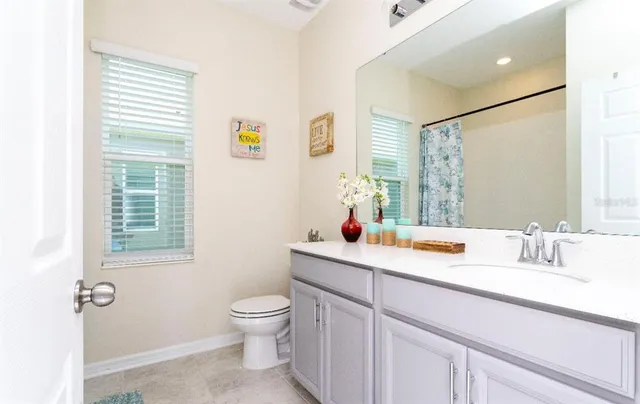 a bathroom with a granite countertop sink mirror vanity and a toilet