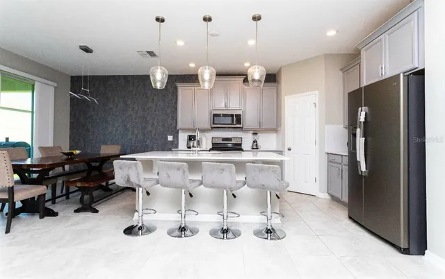 a kitchen with stainless steel appliances kitchen island granite countertop a refrigerator and a sink