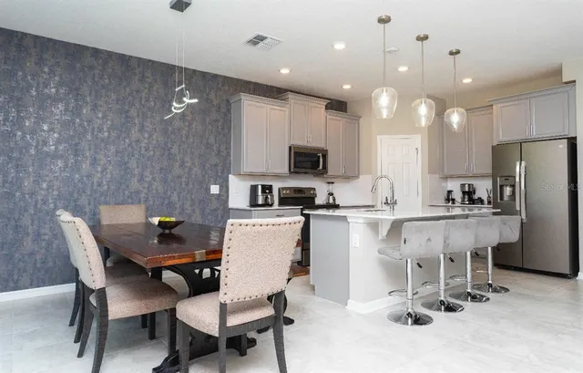 a kitchen with a dining table chairs refrigerator and microwave