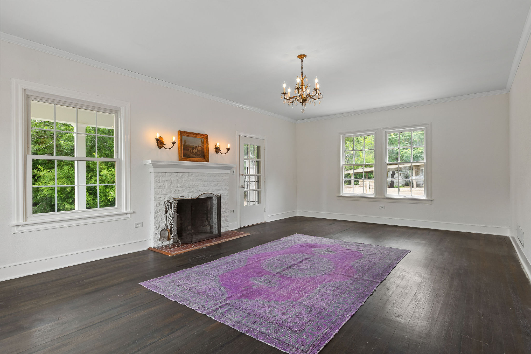 948 Maple Street Lockhart, TX 78644 - Photo 8 of 40 A well-lit living space features rich hardwood floors and a white brick fireplace.