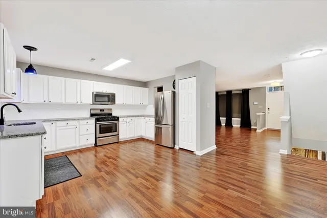 a kitchen with granite countertop appliances cabinets and a wooden floor