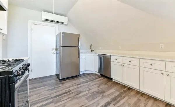 a kitchen with white cabinets and wooden floor