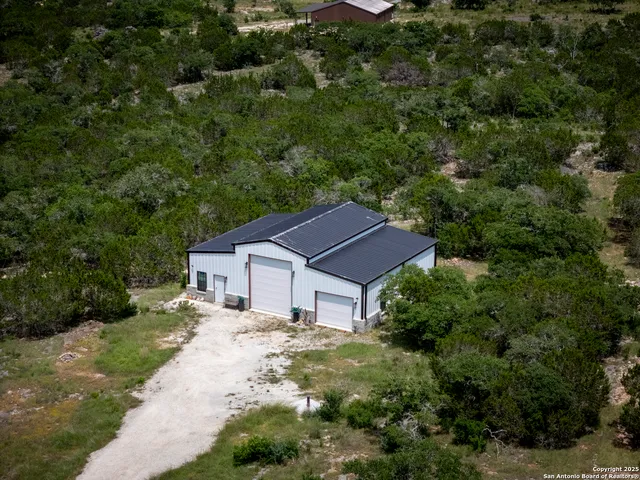 an aerial view of residential houses with outdoor space and trees