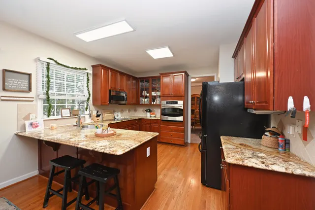 a kitchen with granite countertop kitchen island stainless steel appliances a sink stove and refrigerator