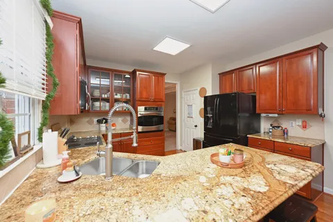 a kitchen with stainless steel appliances kitchen island granite countertop a refrigerator and a sink