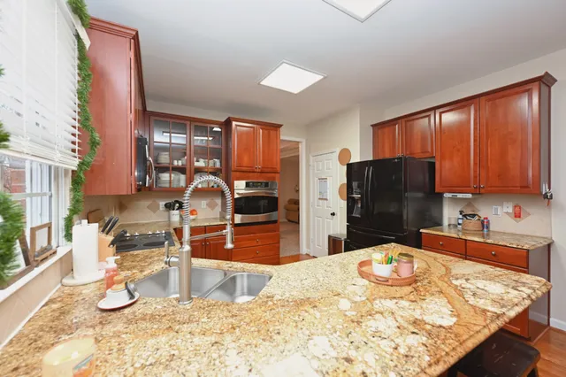 a kitchen with stainless steel appliances kitchen island granite countertop a refrigerator and a sink