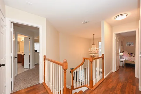 a view of a hallway view with wooden floor and a living room
