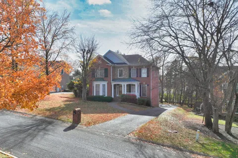 a front view of a house with a yard and large tree