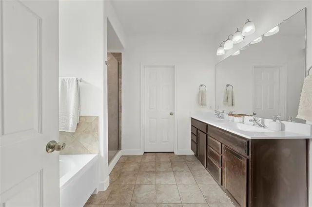 a en suite bathroom with a double vanity sink a large mirror and a bathtub