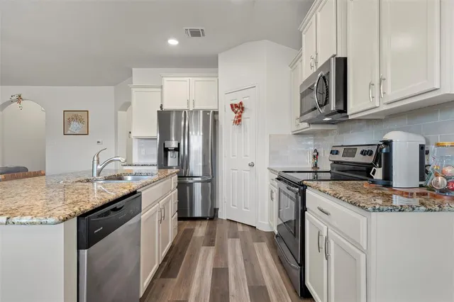 a kitchen with stainless steel appliances granite countertop a sink stove refrigerator and cabinets