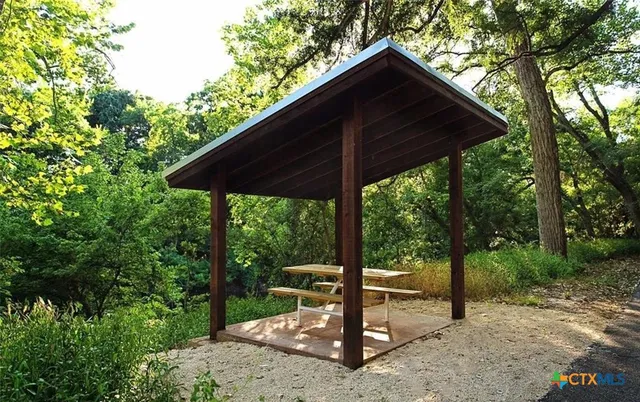 a backyard of a house with a table and chairs under an umbrella